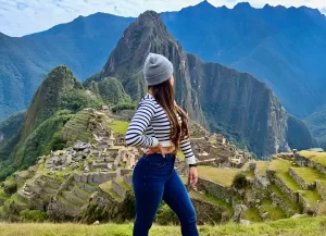 Turista explorando Machu Picchu con clima soleado en julio